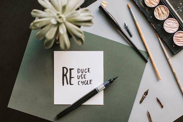 A white paper and a black pen near a plant on a table