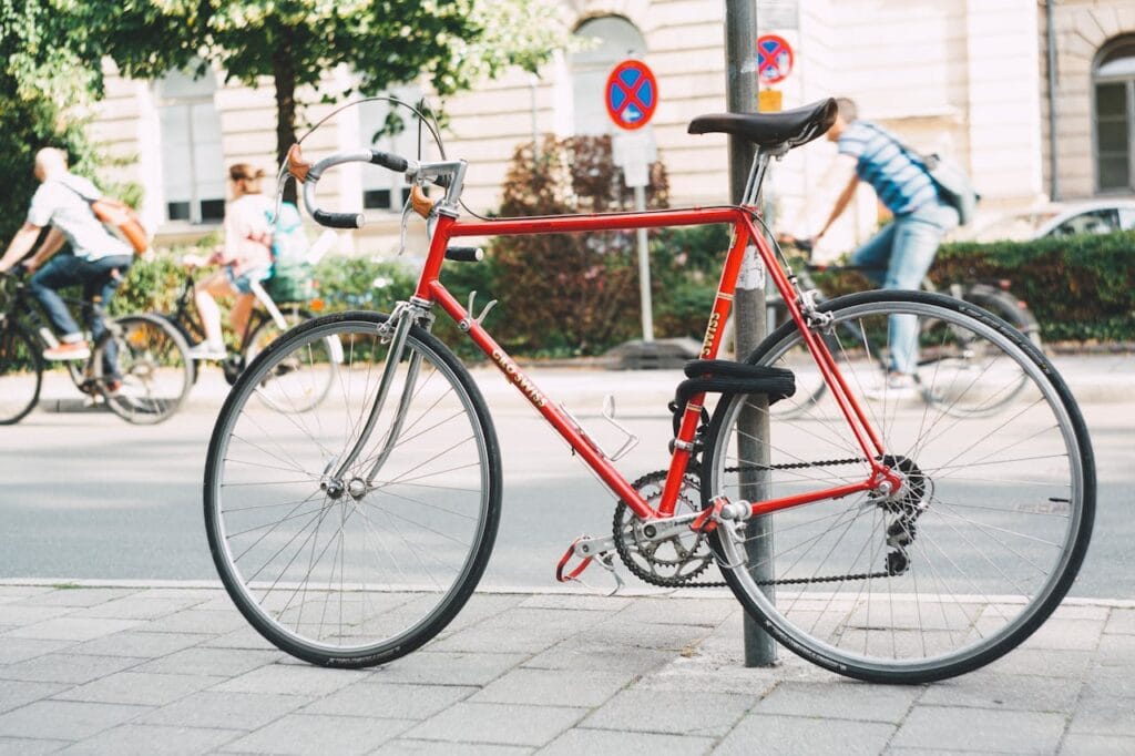 Red bicycle on a post, people biking
