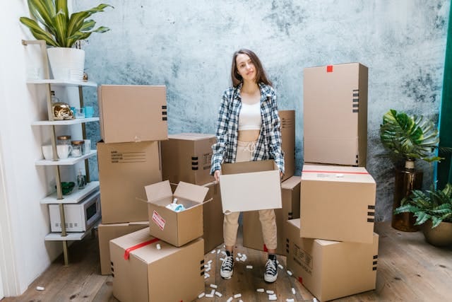 A girl standing between cardboard boxes