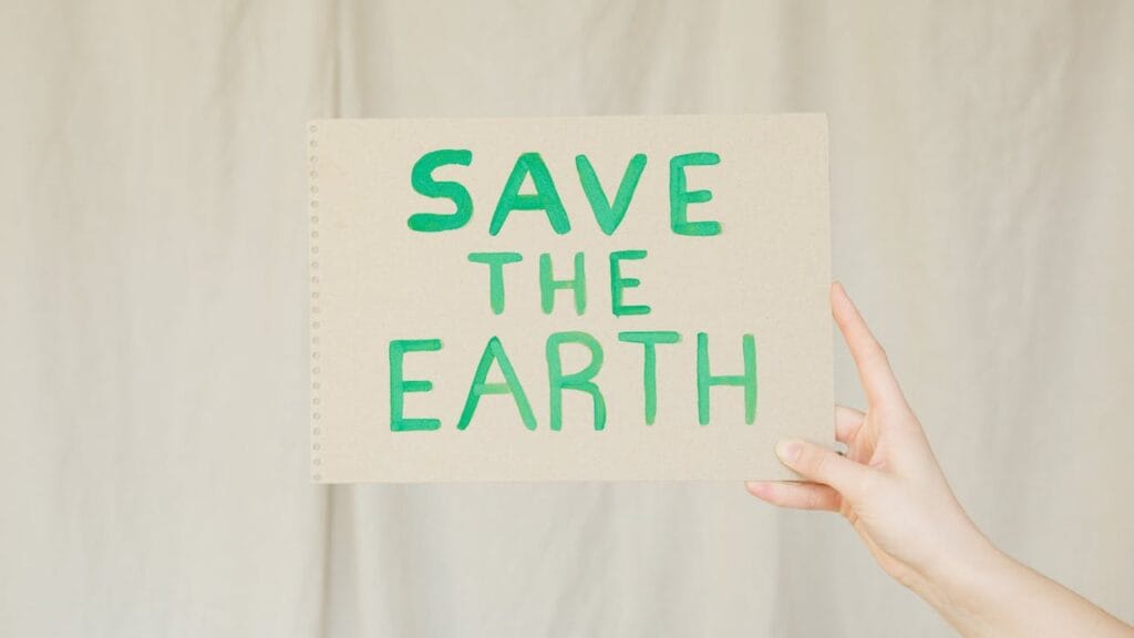 A person holding a save the Earth " poster